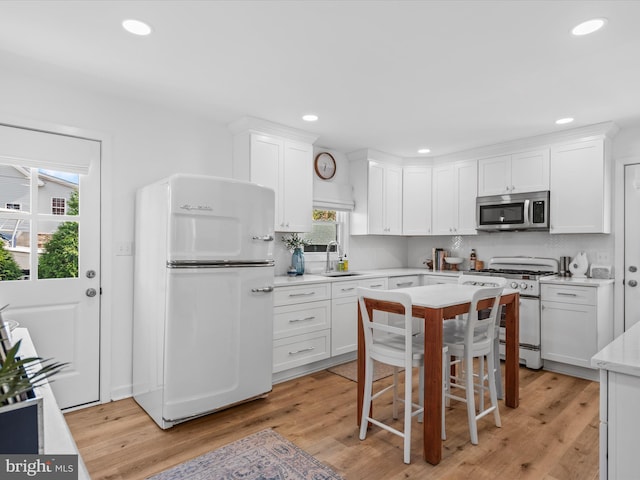 kitchen with sink, stainless steel appliances, light hardwood / wood-style floors, and white cabinets