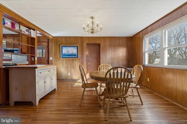 dining room with wood walls, a chandelier, and light wood-type flooring