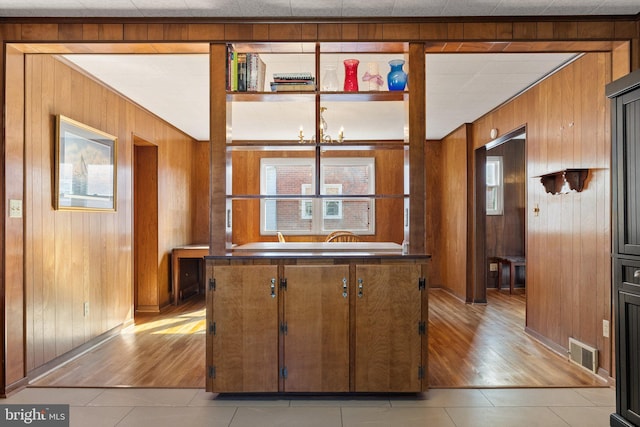 kitchen with a notable chandelier, light hardwood / wood-style floors, and wood walls