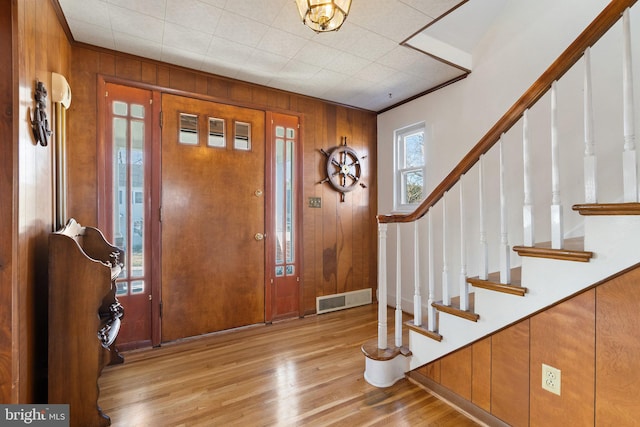 entrance foyer featuring light wood-type flooring and wood walls