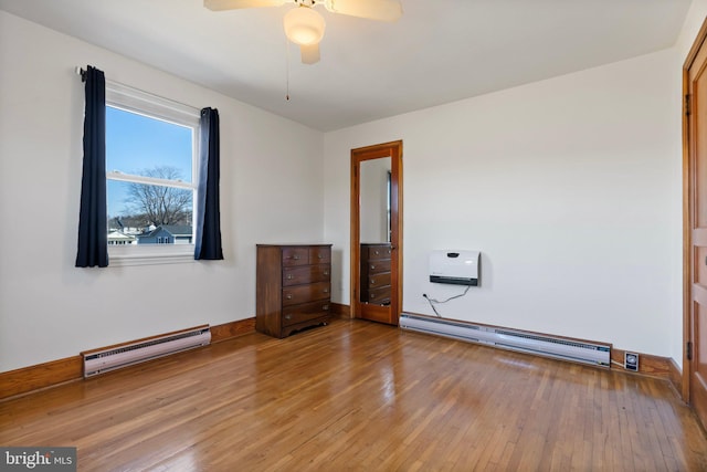 spare room with hardwood / wood-style floors, ceiling fan, and baseboard heating