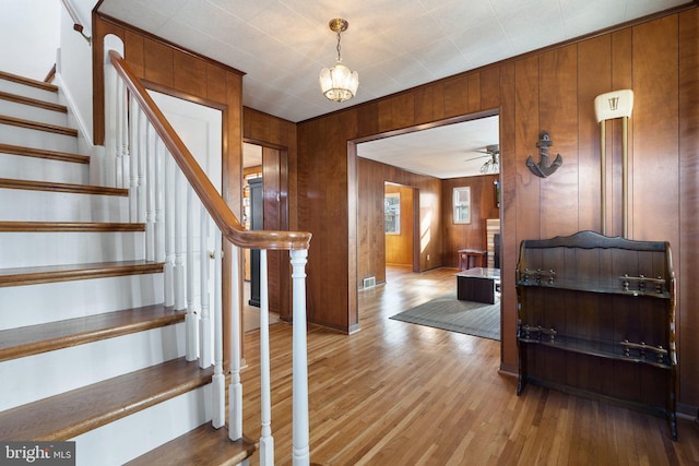 stairway with hardwood / wood-style floors and ceiling fan with notable chandelier