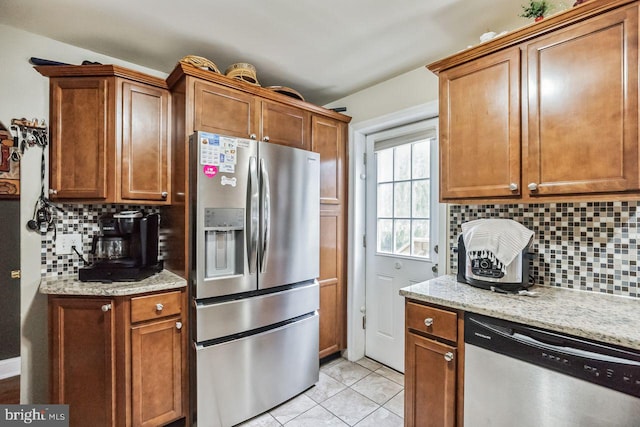 kitchen featuring light stone counters, decorative backsplash, light tile patterned flooring, and appliances with stainless steel finishes