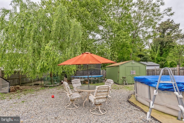 view of patio / terrace featuring a storage shed, a covered pool, and a trampoline