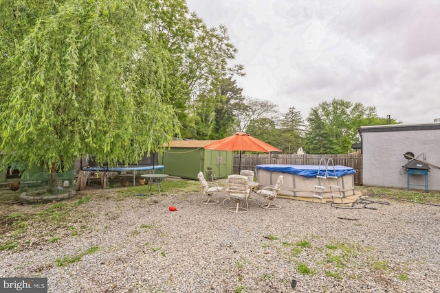 view of yard featuring a trampoline and a covered pool