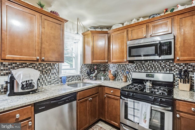 kitchen featuring tasteful backsplash, sink, stainless steel appliances, and light stone countertops