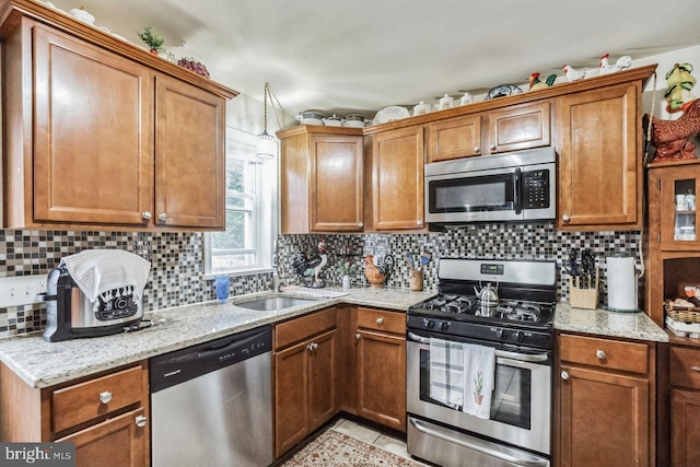 kitchen with sink, decorative backsplash, light tile patterned floors, stainless steel appliances, and light stone countertops