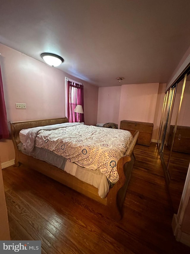 bedroom with dark hardwood / wood-style floors and a closet