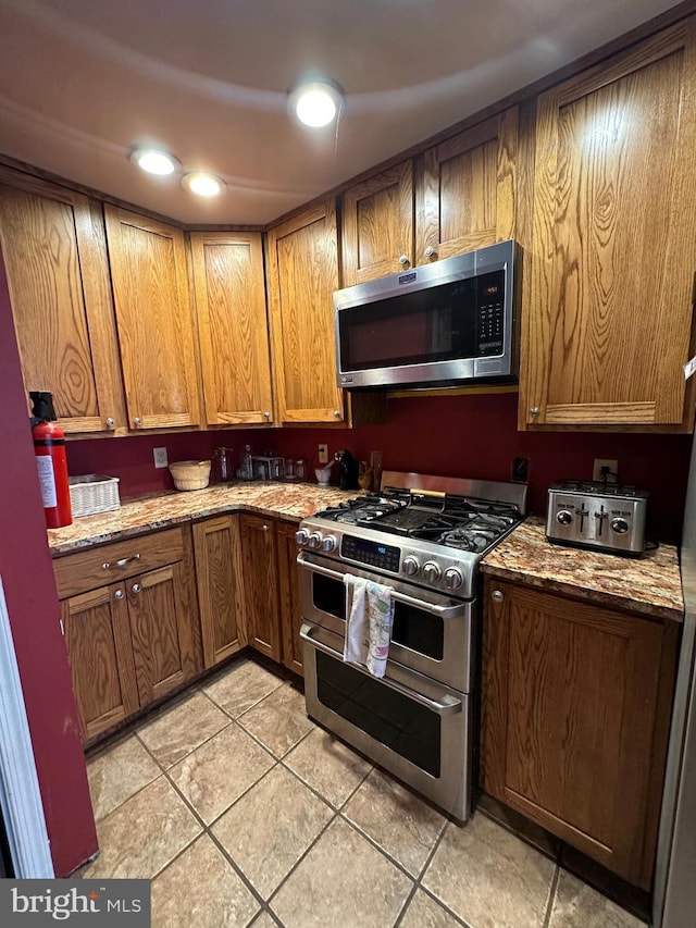 kitchen with light stone counters, light tile patterned floors, and stainless steel appliances