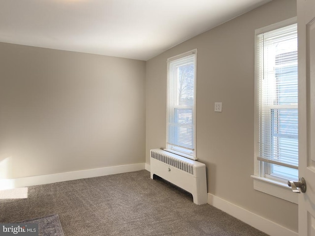 empty room featuring carpet flooring and radiator heating unit