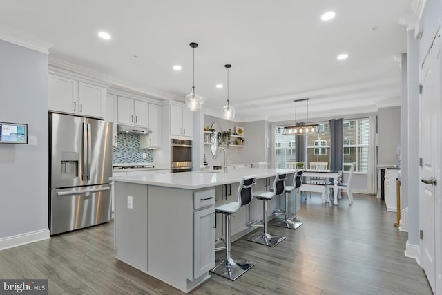 kitchen with stainless steel appliances, white cabinetry, hanging light fixtures, and a spacious island