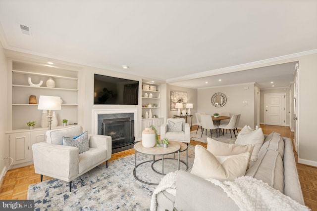 living room with built in shelves, a premium fireplace, crown molding, and light parquet floors