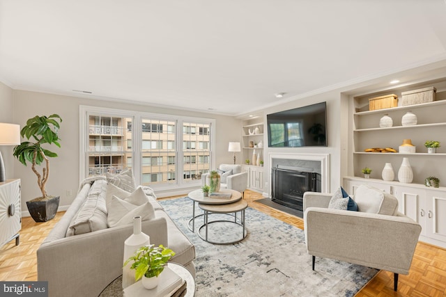 living room featuring ornamental molding, light parquet flooring, a fireplace, and built in features