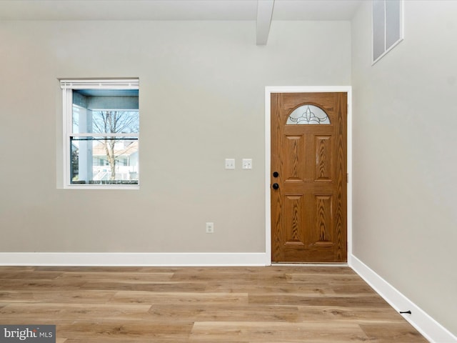 foyer featuring beam ceiling, baseboards, visible vents, and light wood finished floors