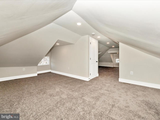 bonus room featuring vaulted ceiling and dark colored carpet