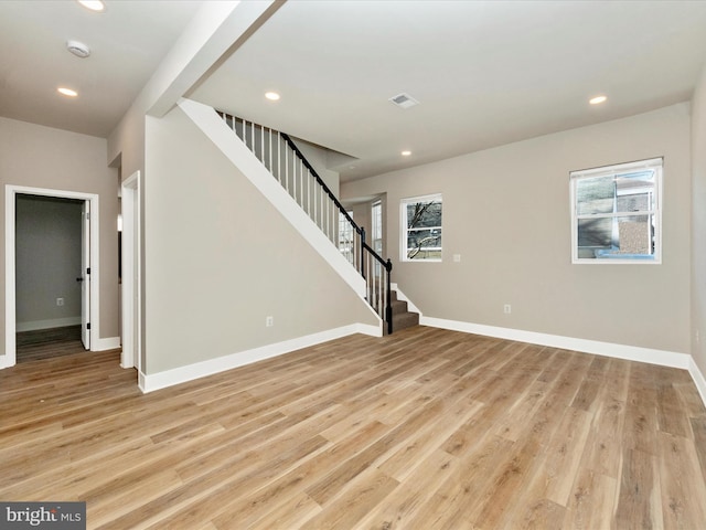 unfurnished living room featuring visible vents, baseboards, stairway, light wood-type flooring, and recessed lighting