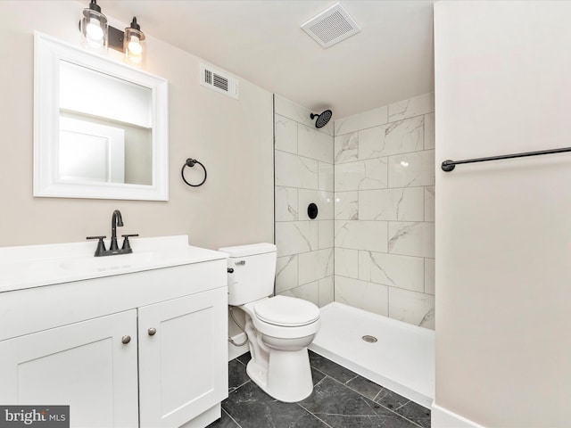 bathroom with tiled shower, vanity, and toilet