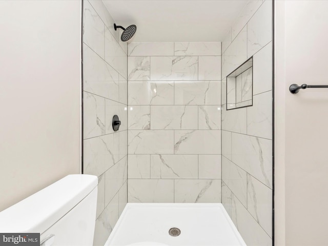 bathroom with toilet and a tile shower