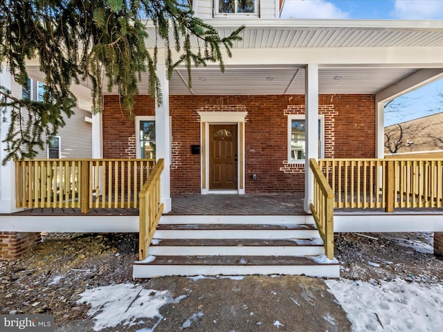 snow covered property entrance featuring a porch