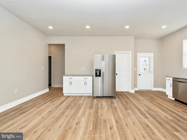 kitchen with white cabinetry, stainless steel appliances, and light hardwood / wood-style flooring