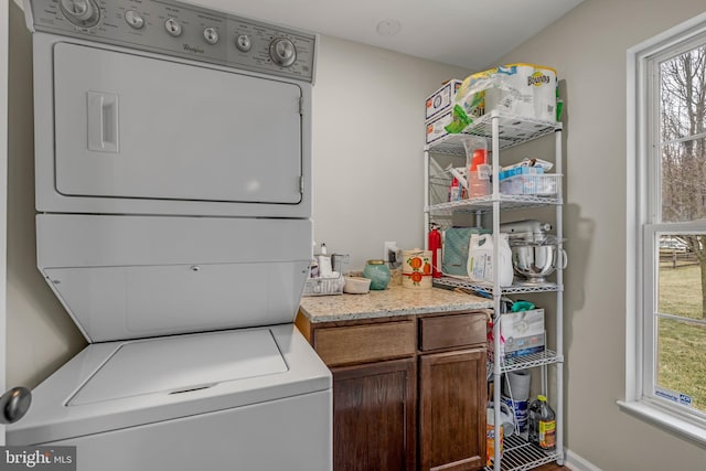 laundry room with cabinets and stacked washing maching and dryer