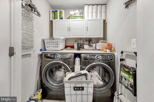 clothes washing area featuring cabinets and washing machine and clothes dryer