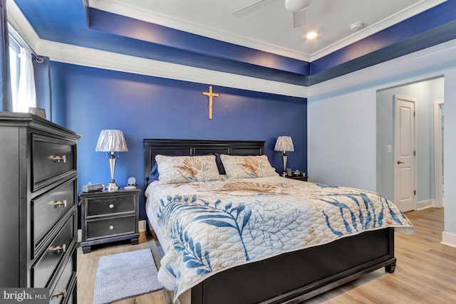 bedroom featuring a tray ceiling, light hardwood / wood-style flooring, and ceiling fan