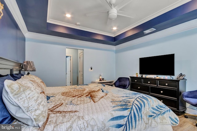 bedroom with ceiling fan, ornamental molding, a raised ceiling, and light hardwood / wood-style flooring