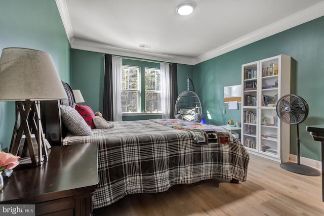 bedroom with crown molding and light hardwood / wood-style floors