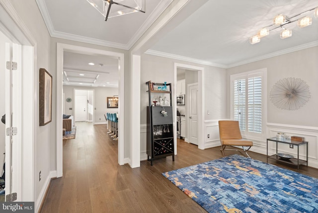 sitting room featuring ornamental molding, wood-type flooring, and a chandelier