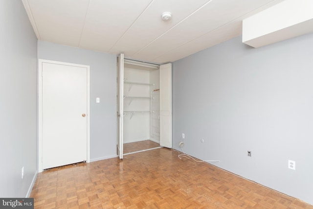 unfurnished bedroom with parquet flooring and a closet