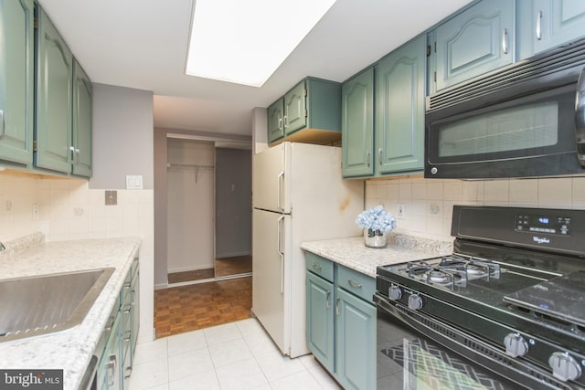 kitchen with tasteful backsplash, black appliances, sink, light stone counters, and green cabinetry