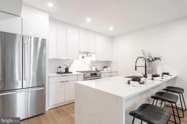 kitchen with light stone counters, sink, stainless steel appliances, and white cabinets