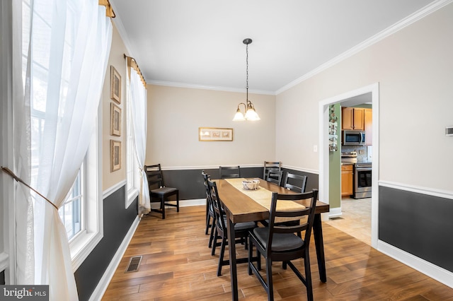 dining space with ornamental molding, a notable chandelier, and light hardwood / wood-style floors