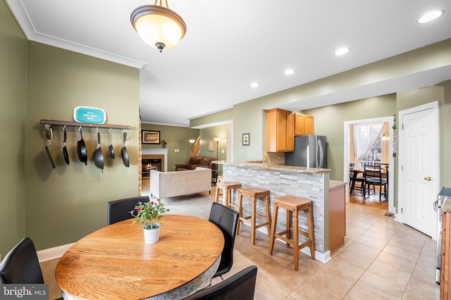 dining space featuring ornamental molding and light tile patterned flooring