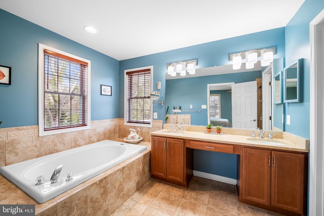 bathroom with tile patterned flooring, vanity, and a relaxing tiled tub