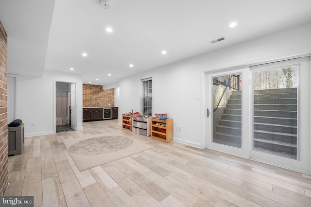 interior space with brick wall and light hardwood / wood-style flooring