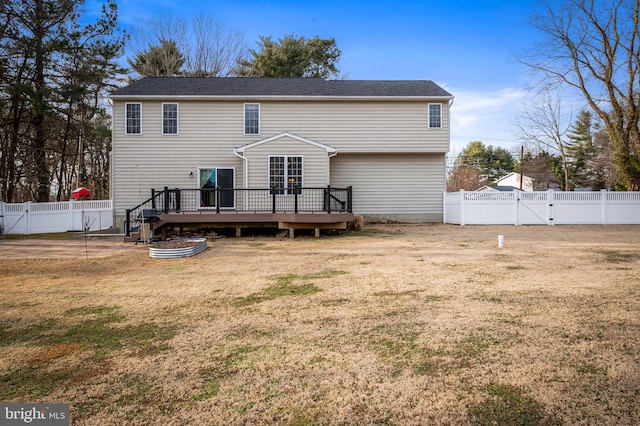 rear view of house featuring a wooden deck and a yard