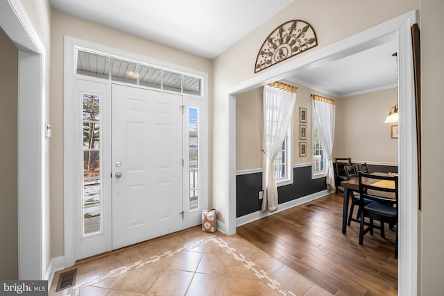 foyer with hardwood / wood-style flooring, ornamental molding, and plenty of natural light