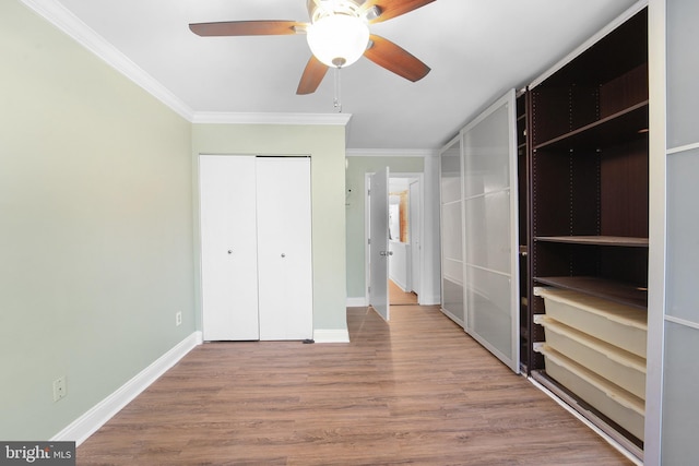 unfurnished bedroom with crown molding, a closet, ceiling fan, and hardwood / wood-style flooring