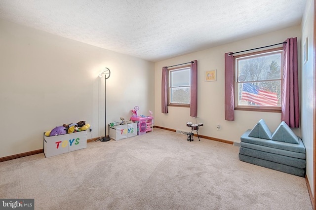 recreation room with light colored carpet and a textured ceiling