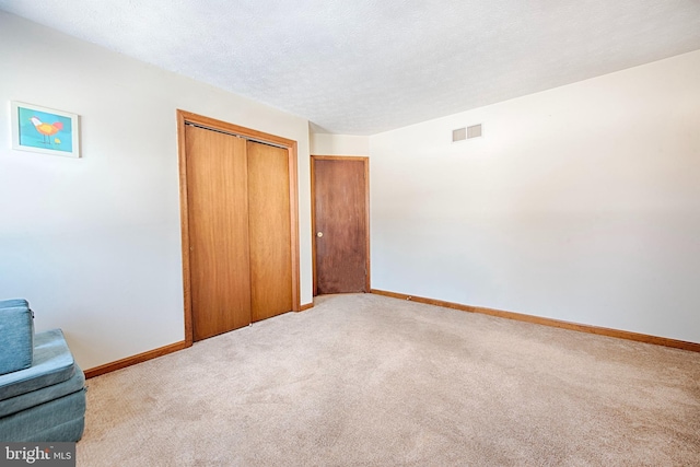 unfurnished bedroom with light colored carpet, a closet, and a textured ceiling