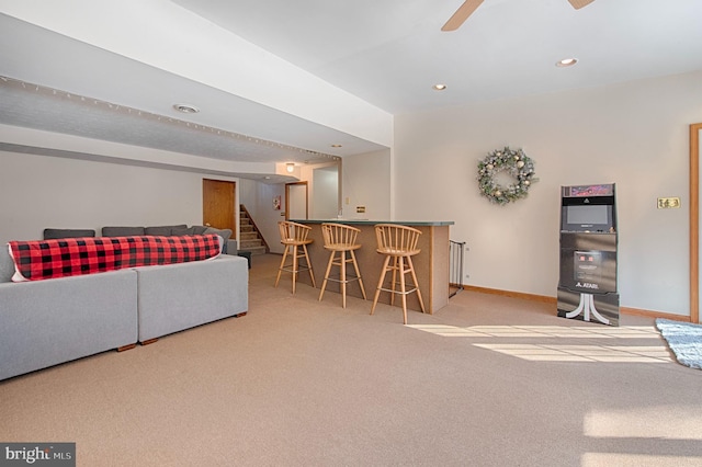 living room with light colored carpet, ceiling fan, and bar area