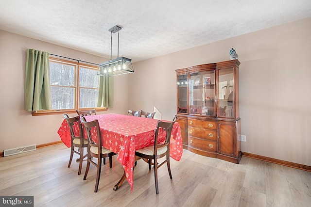 dining space featuring light hardwood / wood-style flooring and a textured ceiling