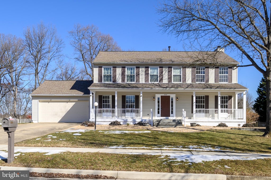 colonial home featuring a garage, a front yard, and covered porch