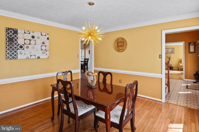 dining area with wood-type flooring, ornamental molding, and an inviting chandelier