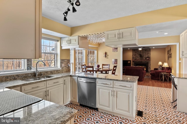 kitchen featuring sink, kitchen peninsula, dishwasher, ceiling fan, and a fireplace