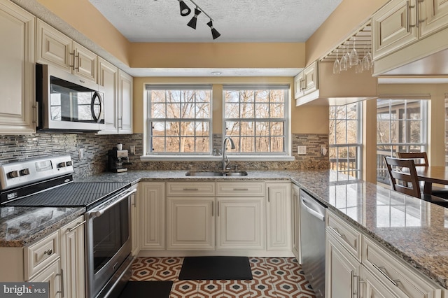 kitchen featuring stainless steel appliances, light stone countertops, and cream cabinets