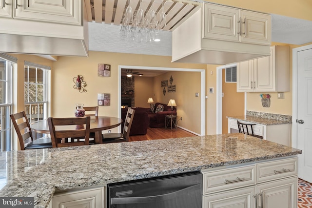 kitchen featuring ceiling fan, dishwasher, light stone countertops, a textured ceiling, and cream cabinetry