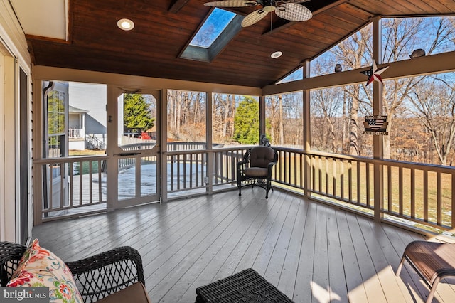 unfurnished sunroom featuring lofted ceiling with skylight, a wealth of natural light, wooden ceiling, and ceiling fan